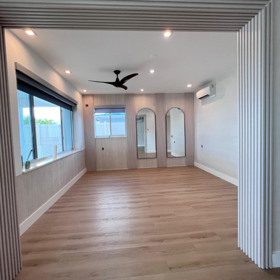 Main room with wood floor, light slat wall decoration, and large windows.