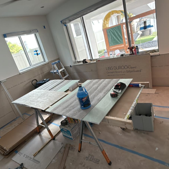 Room during construction with drywall installed and a work table in the center.