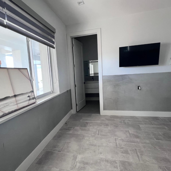 Room with a painting resting on the window sill and a view into an adjacent bathroom.